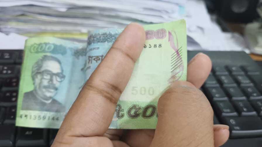Hand checking a suspected counterfeit banknote during retail cash reconciliation