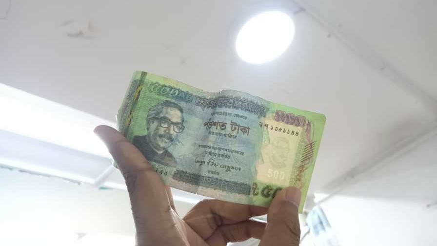 Retail worker checking a suspicious banknote under light during a busy retail shift